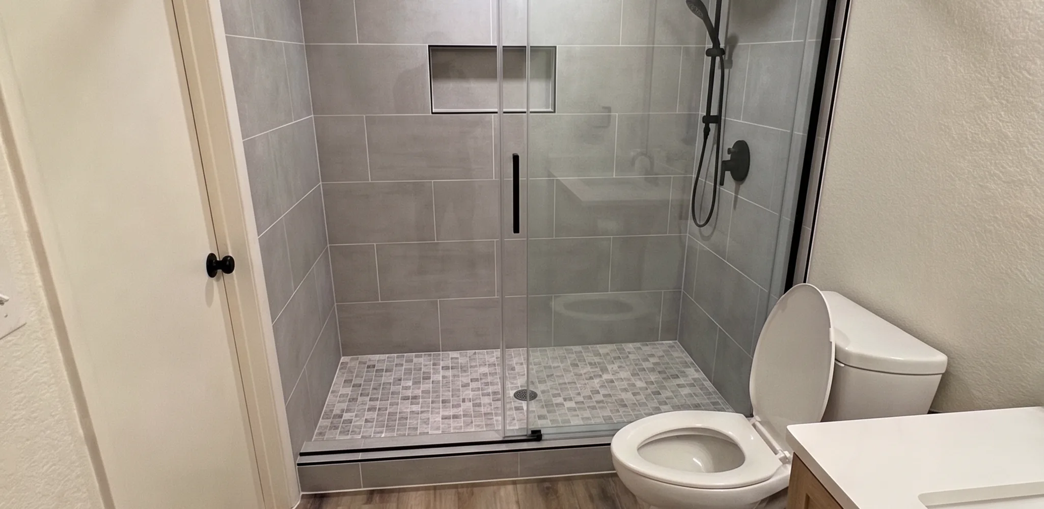Finished walk-in shower with large format porcelain tile where a bathtub used to sit
