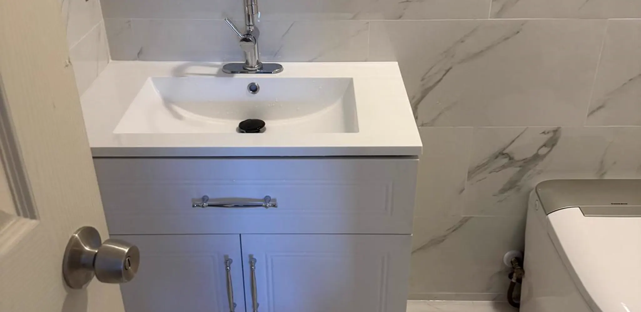 Compact bathroom finished with a vanity and porcelain tile carried up the wall