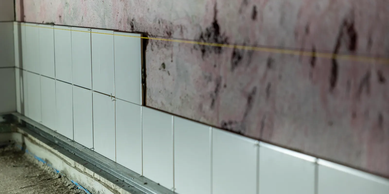 Old wall tile stripped off, showing the damaged wall behind it, bathroom remodel cost