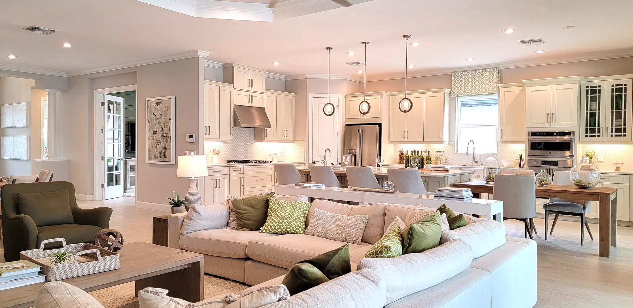 A large living room open to a white kitchen and a dining table, home remodeling