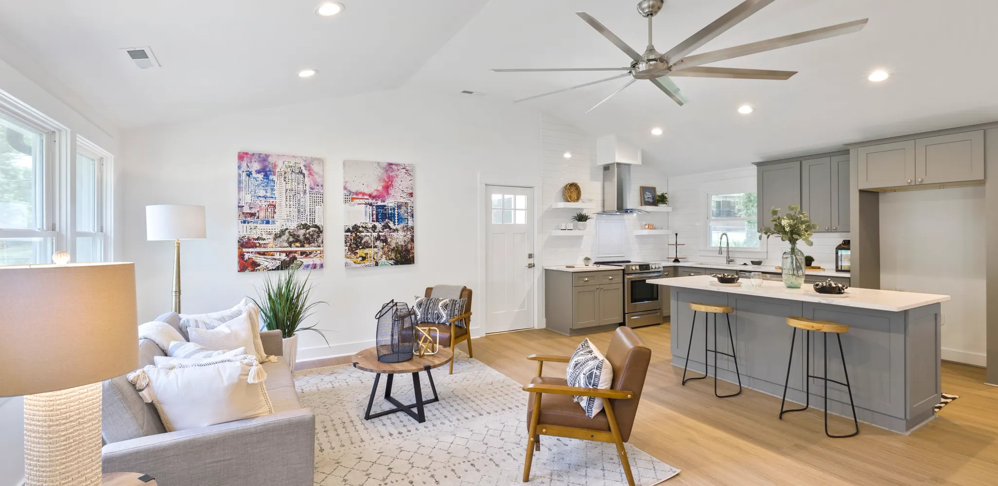 A living room with a high ceiling open to a gray kitchen, home remodeling