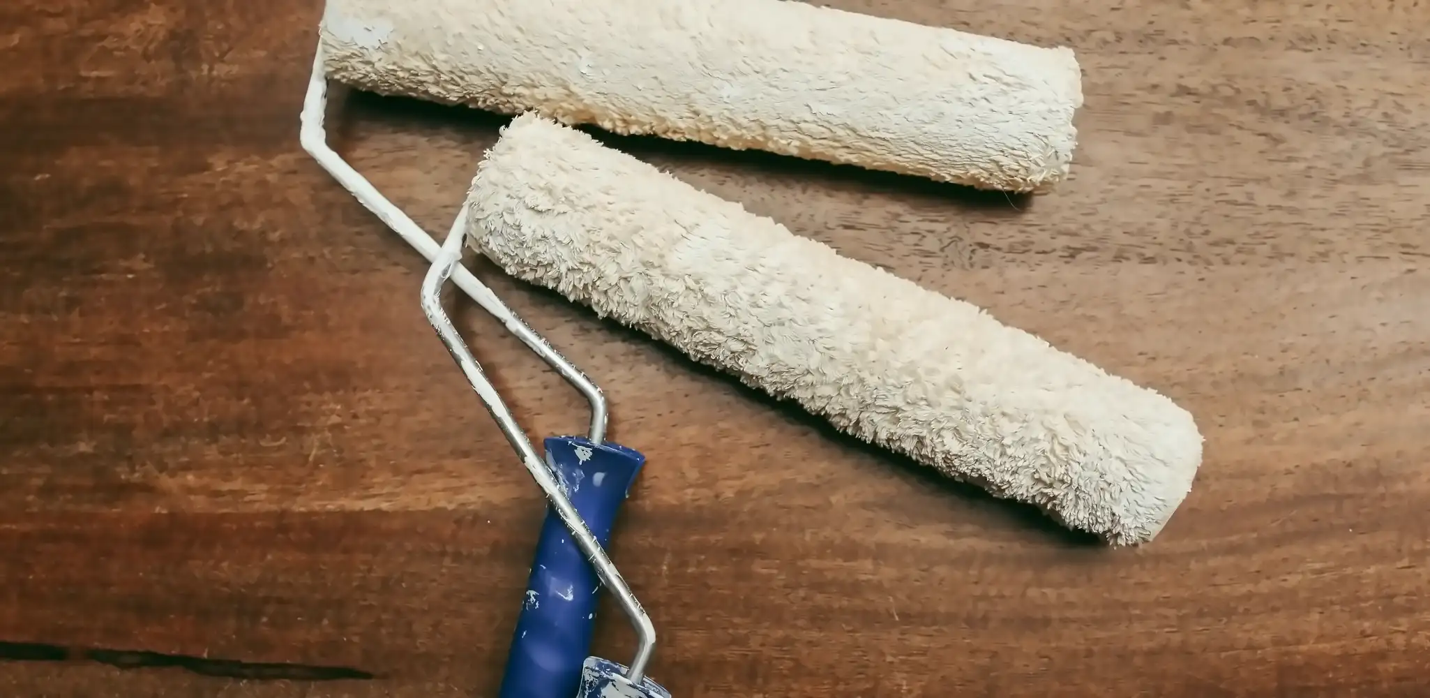 Two paint rollers on a wood surface, interior and exterior painting