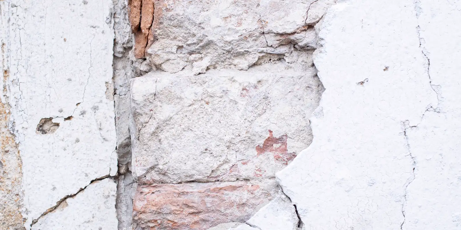 Close up of a cracked stucco wall before repair, exterior painting