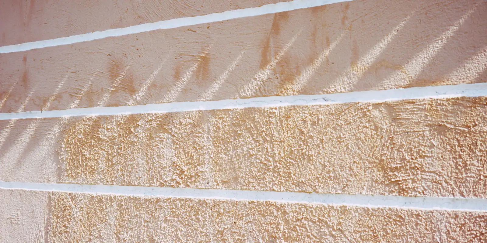 A stucco wall in full sunlight showing its texture before washing, exterior painting