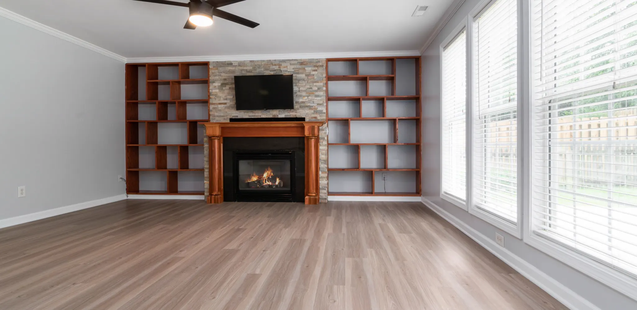 An empty living room with a light plank floor and a fireplace, flooring cost