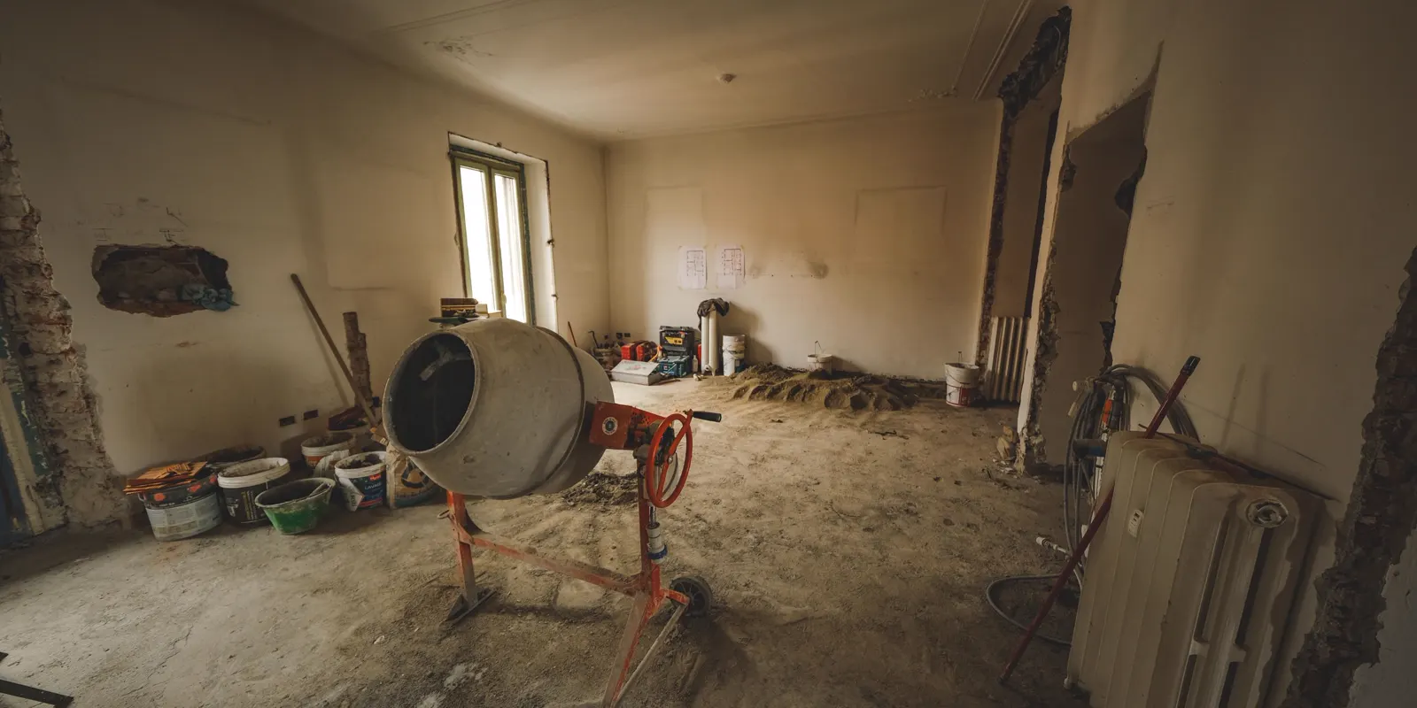 An empty room with a concrete mixer and tools on a bare floor, flooring cost