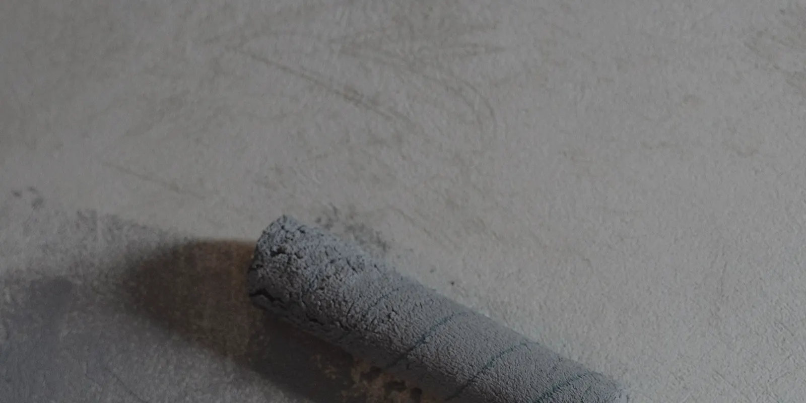 Close up of a paint roller applying a gray primer coat, interior painting