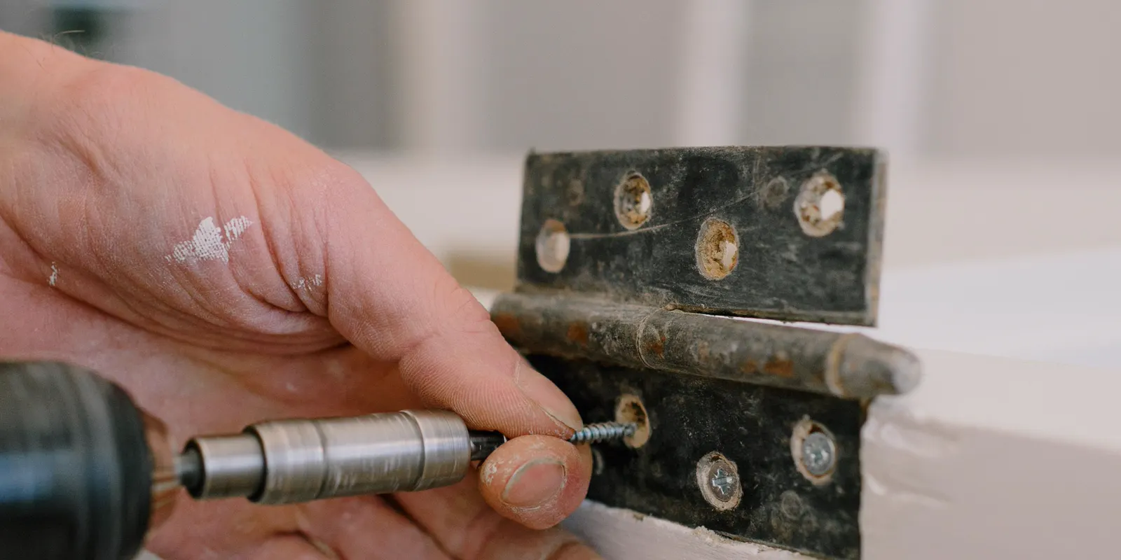 A carpenter's hands fitting a hinge on a cabinet door, kitchen cabinet door replacement