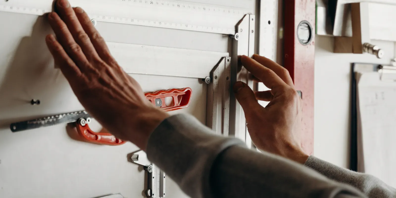 Hands using measuring tools against a wall before a template, kitchen countertop installation