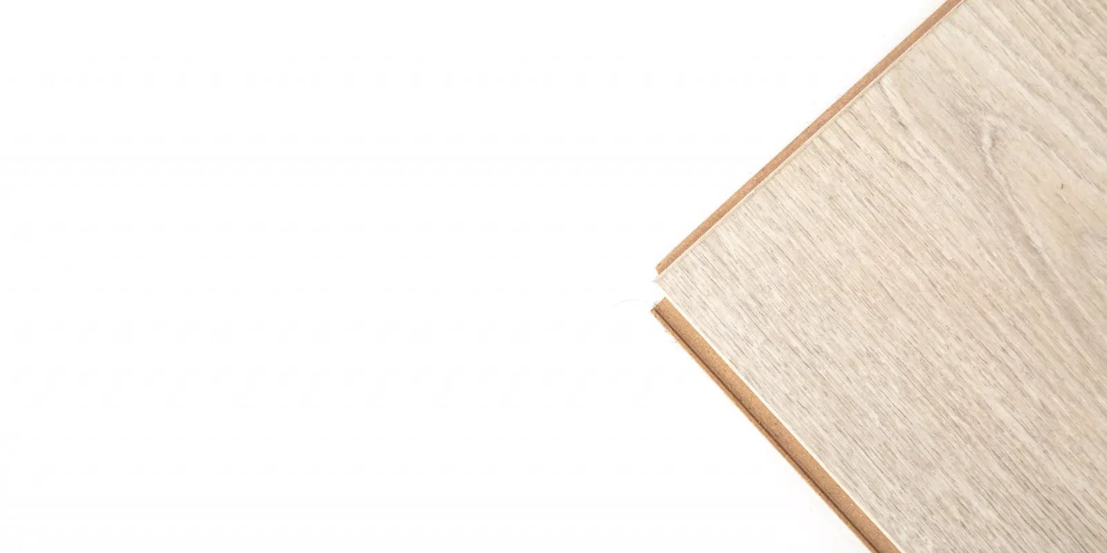 Close up of the edge of a light wood plank showing its core, laminate flooring