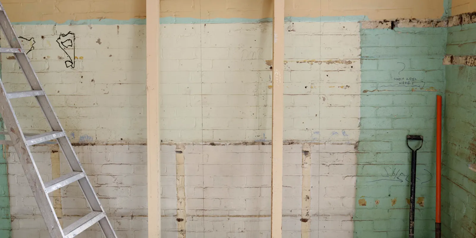 A room stripped to the framing with a ladder, shower replacement