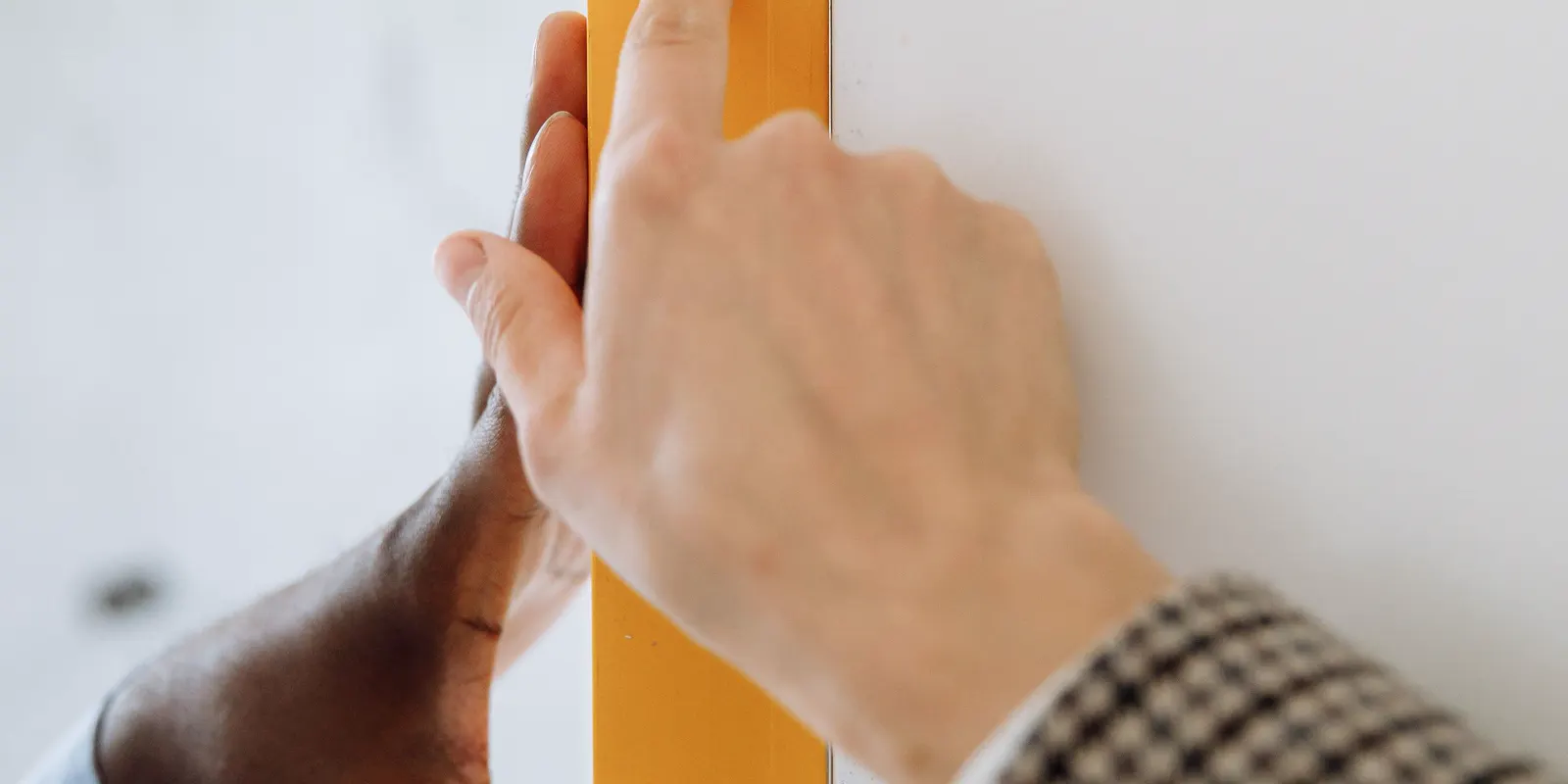 Hands holding a yellow bubble level to check a surface, tile flooring installation