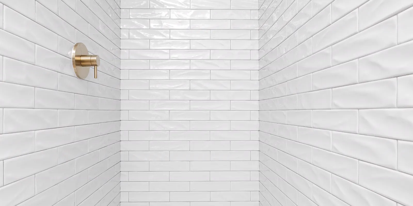 A white tiled walk in shower with no curb, walk in shower